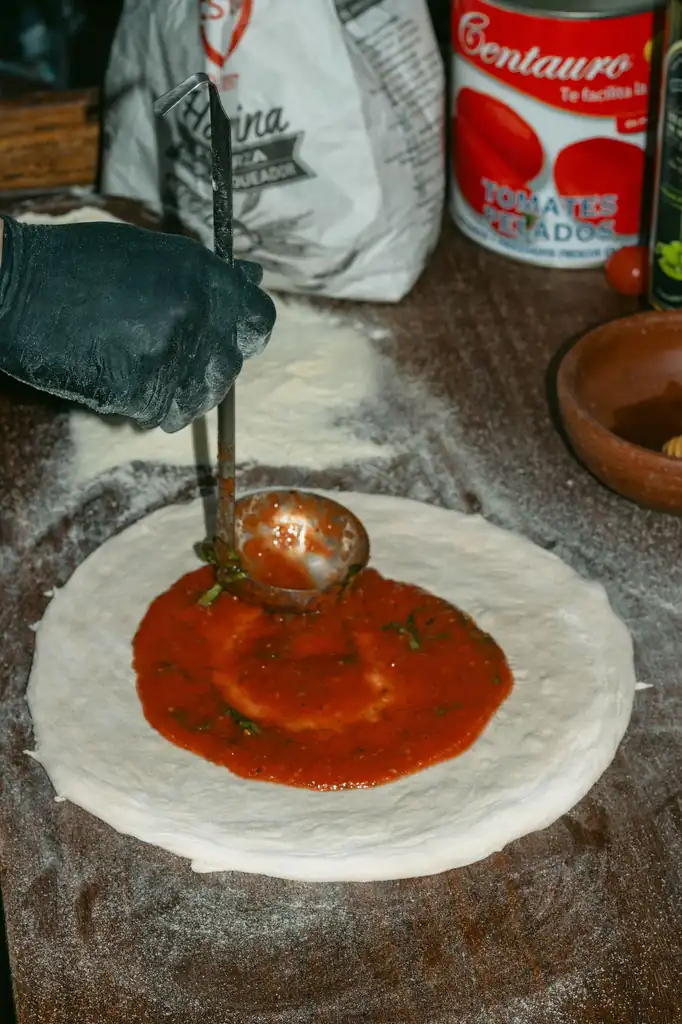 Tomaattikastikkeen tasainen levitys pyöreälle pizzapohjalle