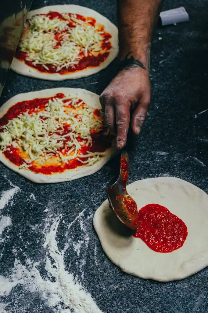 Tomaattikastikkeen levittäminen pizzapohjalle